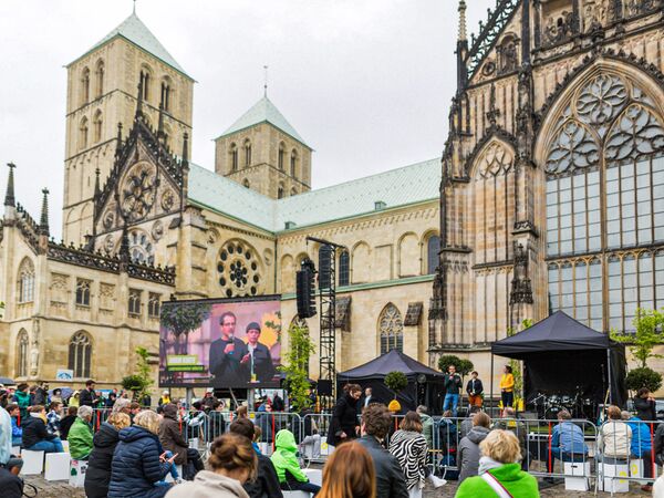 Menschen stehen vor einer LED Wand am Dom zu Münster